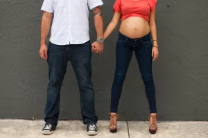 Couple holding hands with pregnant belly showing